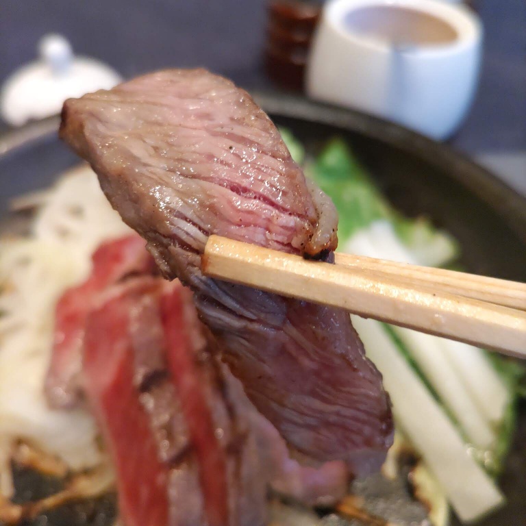 神戸牛ロースステーキを鉄皿で熱してからお箸で挟んで今まさに食べようとするところ