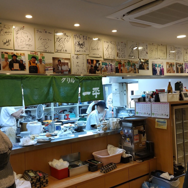グリル一平新開地本店厨房の様子。壁には有名人の写真とサイン色紙が飾られている。