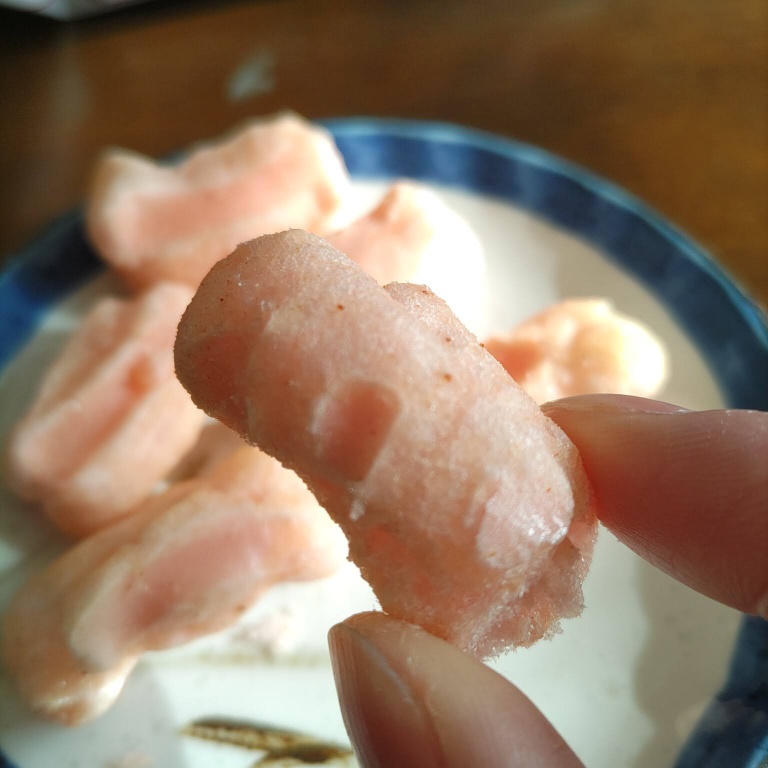 越後製菓海老しお焼きを右手の親指と人差し指でつまんだ時に撮影した写真画像